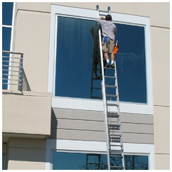 Second story window of a commercial building in Roseville, CA being cleaned by a man on ladder.