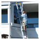 An employee standing on a ladder cleaning a business's windows.